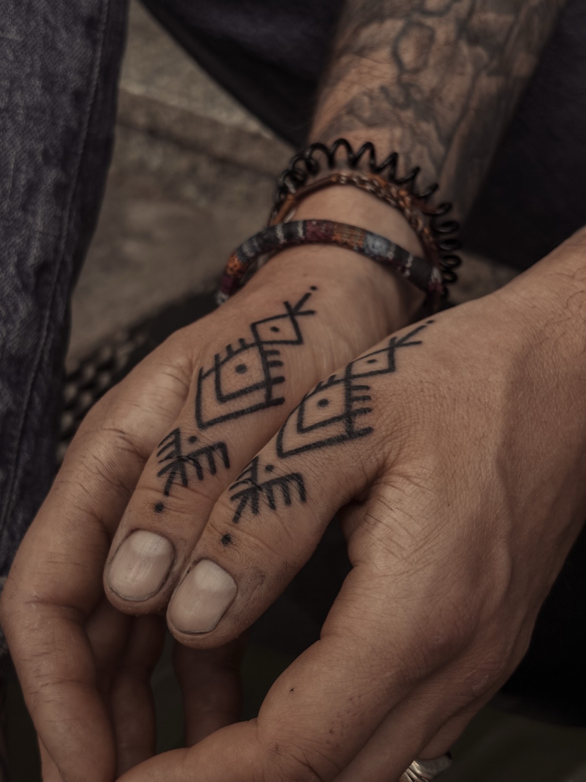 Simboli geometrici tatuati sulle dita di due mani