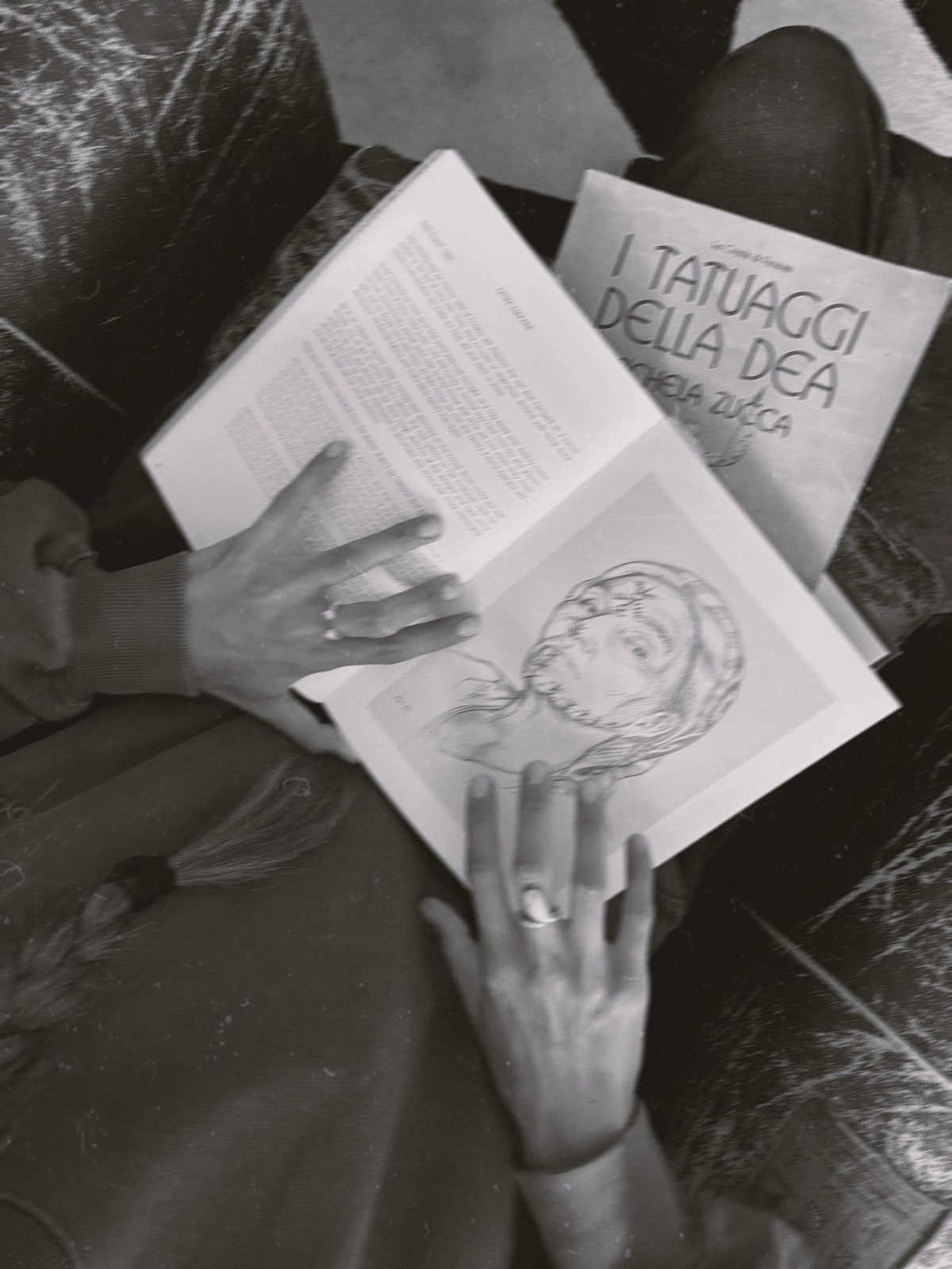 Carlotta sfoglia un libro aperto su un'illustrazione di volto tatuato