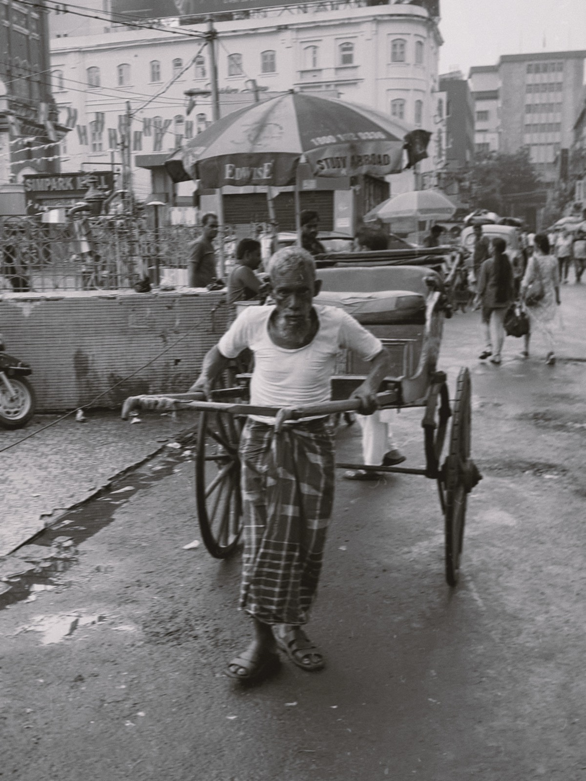 Un uomo tira un risciò lungo una strada affollata, in India